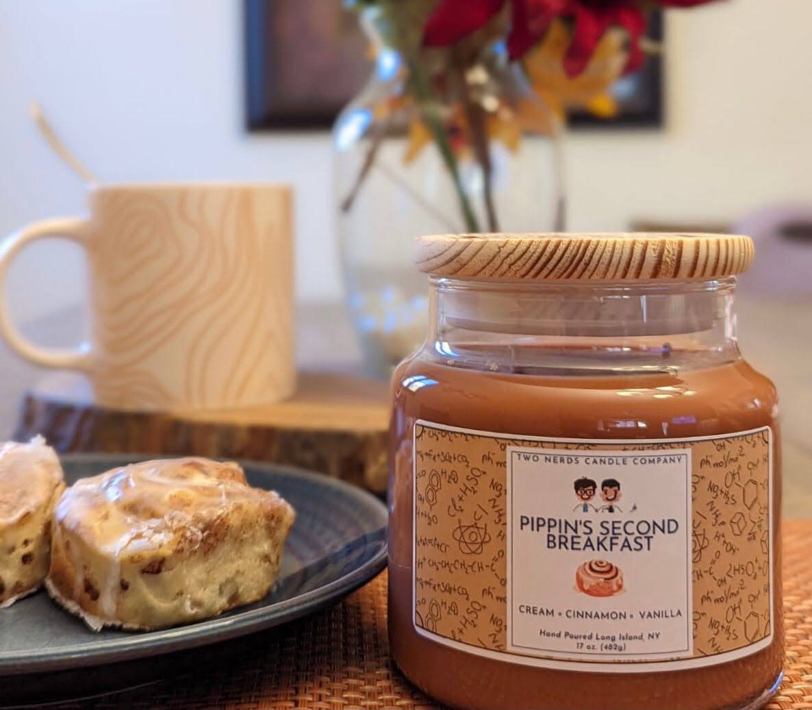 A brown soy candle themed after the Lord of the Rings which is a vanilla cinnamon scented with a cinnamon roll and coffee roll in the photograph.